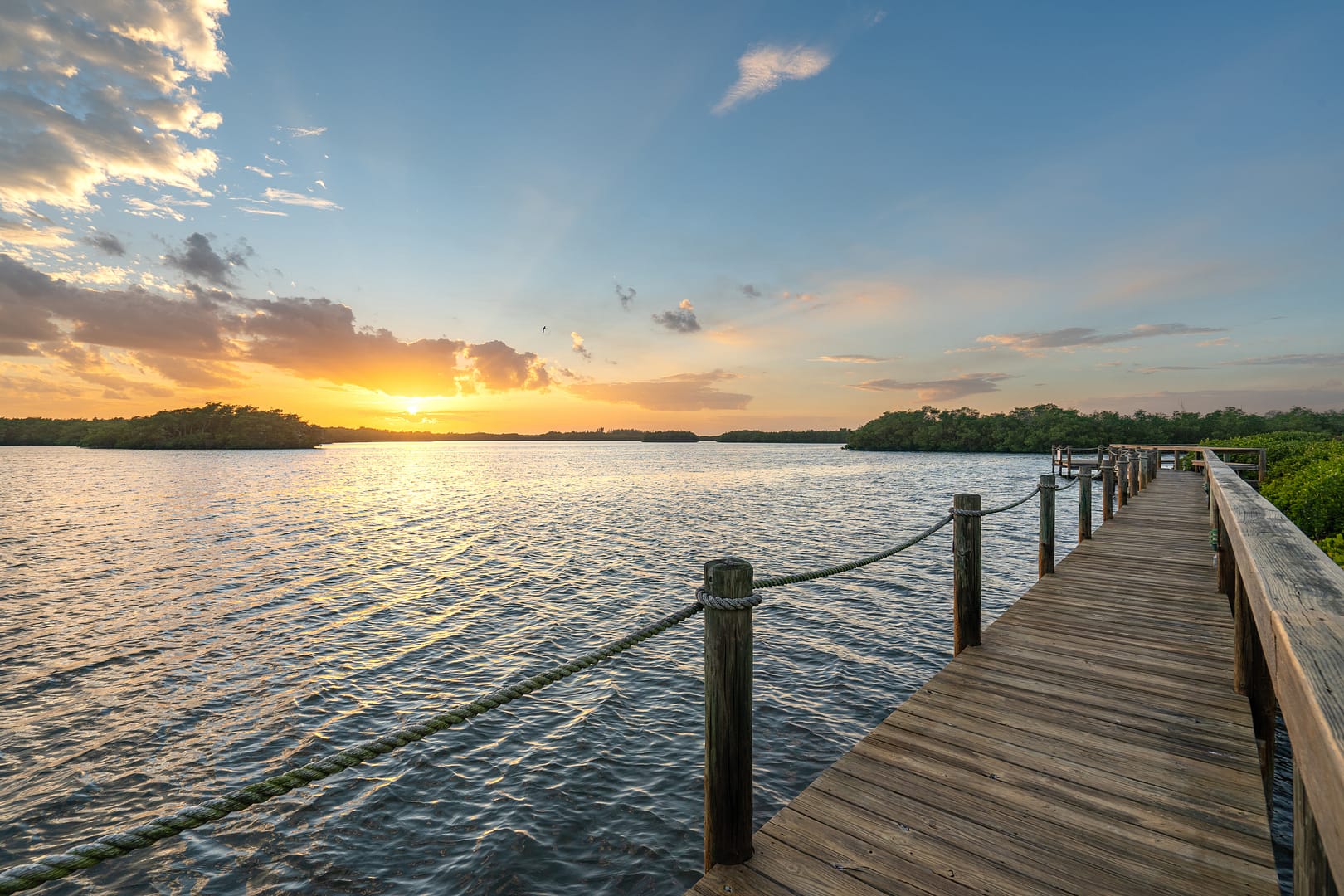 A serene wooden pier on the water at sunset, symbolizing the secure financial landing and fiduciary trust of Capitol Landing Wealth, a fee only financial advisor in Williamsburg VA.